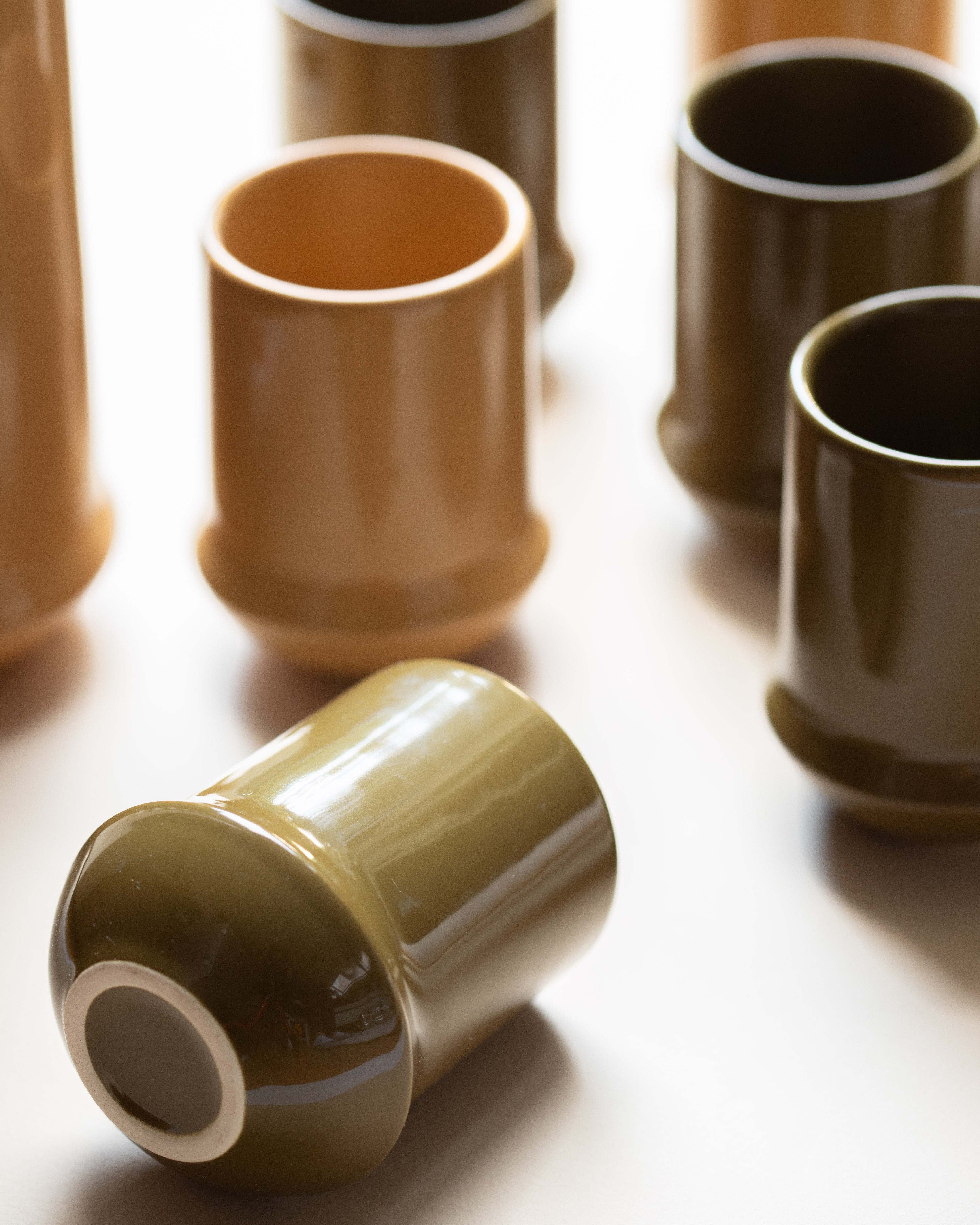 Set of ceramic cups in various shades of brown on a light background