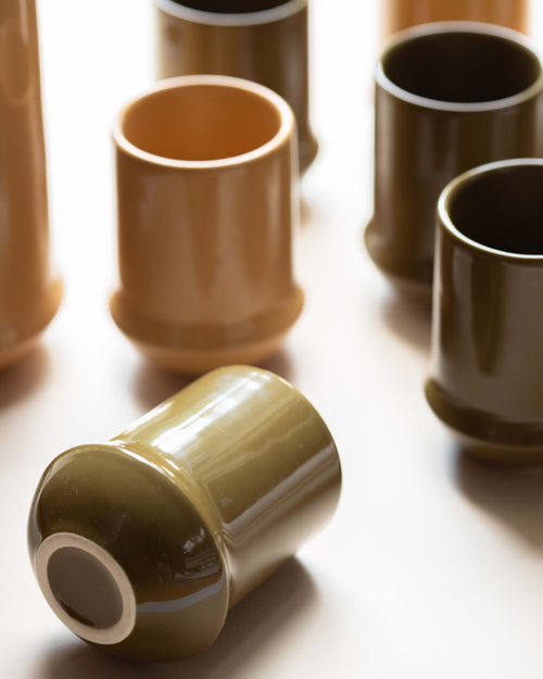 Set of ceramic cups in various shades of brown on a light background