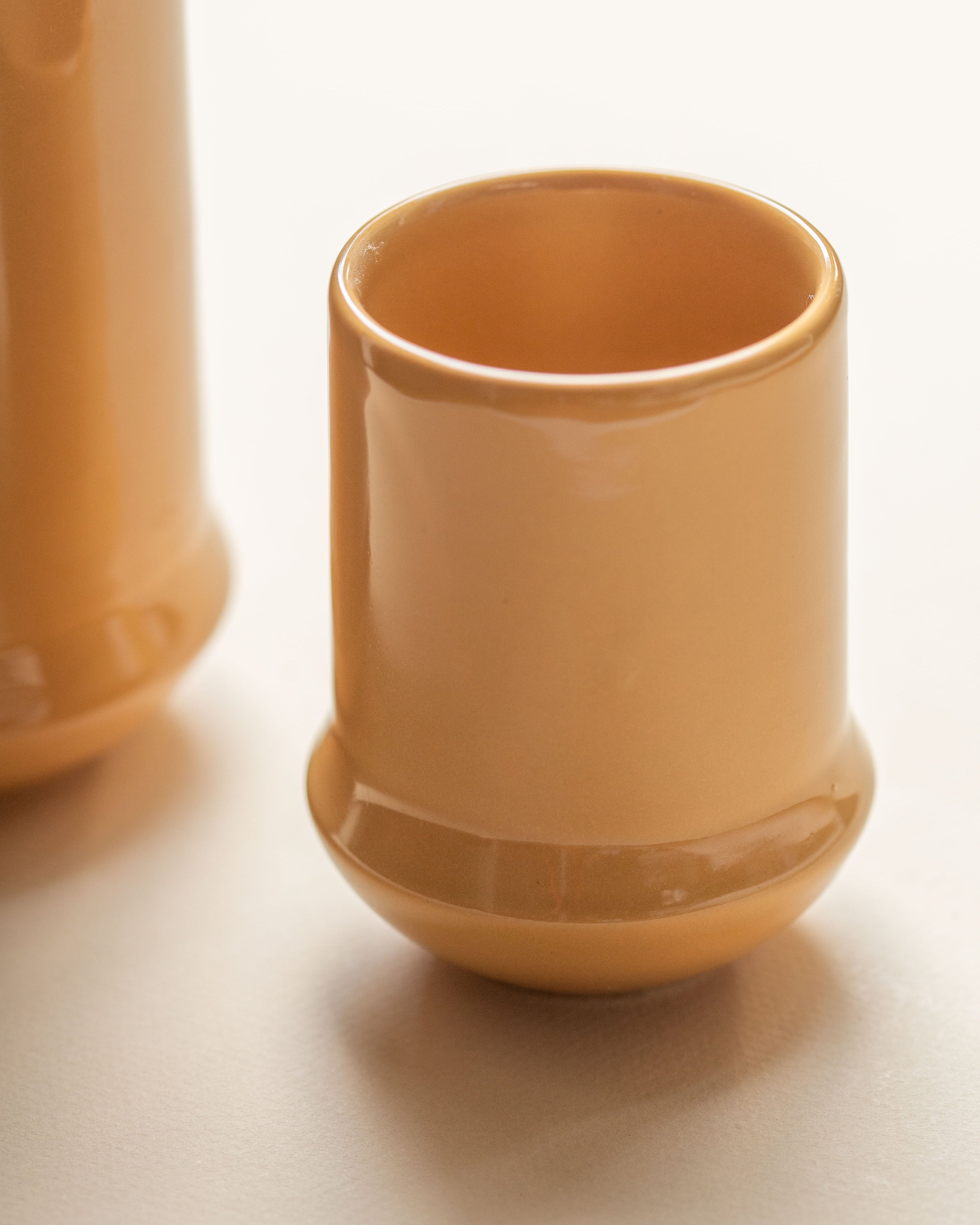 Two yellow mustard ceramic cups on a white background